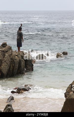 Zipolite, Oaxaca, México; 10 25 2015; Ein Mann, der auf einem Felsen am Strand in Zipolite, Oaxaca, México steht. Stockfoto