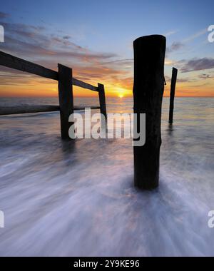 Sonnenuntergang am Strand am Darsser Ort, Zaun und Pfosten an der Ostsee als Grenze der abgesperrten Kernzone des Vorpommerschen Boddenlandschaf Stockfoto