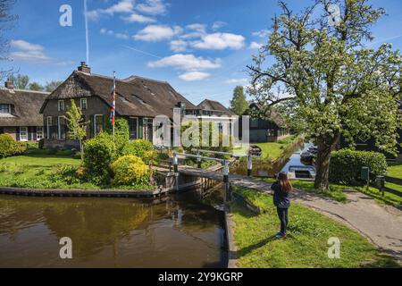 Giethoorn Niederlande, City Skyline am Kanal und traditionelles Haus in Giethoorn Dorf mit Touristen Frau Stockfoto