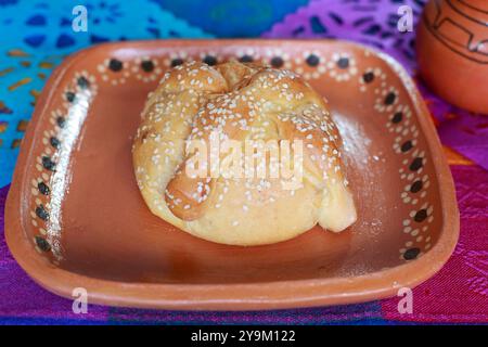 Traditioneller Pan de Muerto auf einer farbenfrohen Tischdecke Stockfoto