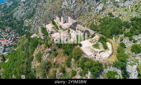 Aus der Vogelperspektive auf die Festung San Giovanni (St. Johannes), die auf einem Felsvorsprung über der Altstadt von Kotor in Montenegro erbaut wurde - mittelalterliche Ruinen überblickend Stockfoto