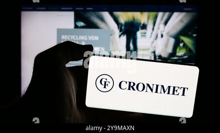 Germany. 7th Aug, 2024. In this photo illustration, a person is holding a mobile phone with the logo of German metal recycling company Cronimet Holding GmbH in front of webpage. (Credit Image: © Timon Schneider/SOPA Images via ZUMA Press Wire) EDITORIAL USAGE ONLY! Not for Commercial USAGE! Stock Photo