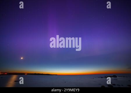 Darstellung von violetten und rosa aurora Borealis über der Ostsee in Estland. Sonnenuntergangsstreifen am Horizont Stockfoto