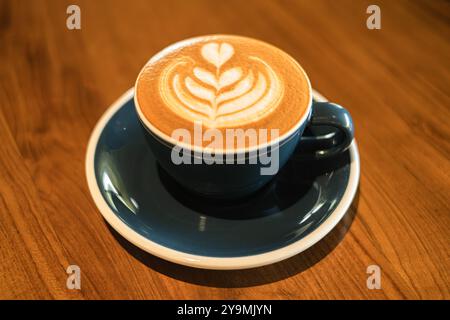 Eine Tasse Kaffee mit herzförmiger Latte Art auf einem Holztisch Stockfoto