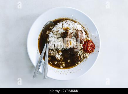 Ein Teller Rawon mit zartem Rindfleisch und Sambal. Traditionelles indonesisches Essen und Gericht. Flacher Lagenwinkel, Überkopf- oder Draufsicht. Stockfoto