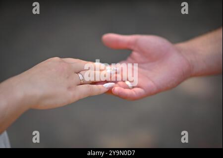 Die Hand einer Frau mit einem Ehering auf der Handfläche eines Mannes. Konzept Stockfoto