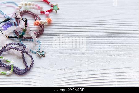 Verschiedene farbenfrohe, handgefertigte Armbänder und Accessoires sind auf einer rustikalen Holzoberfläche angeordnet, die Kreativität und Handwerkskunst in Schmuck zum Ausdruck bringen Stockfoto