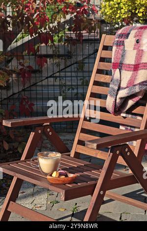 Eine Tasse Cappuccino und Macarons Plätzchen vor dem Hof an sonnigen Herbsttagen. Jahreszeiten und Lebensstil. Schöne Zeit, um sich zu entspannen und die Ruhe zu genießen. Stockfoto