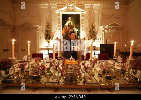 Evan Samson, der das Front-of-House-Team im Dumfries House leitet, zündet Kerzen an, während er dem Pink Dining Room, dem Lieblingszimmer des Königs im Dumfries House in Cumnock, Ayrshire, den letzten Schliff verleiht, wo Mitglieder der Öffentlichkeit die Möglichkeit erhalten, ein fest aus dem 18. Jahrhundert zu genießen, als Teil eines neuen maßgeschneiderten Dining Experience, das von der King's Foundation Charity geleitet wird. Bilddatum: Donnerstag, 10. Oktober 2024. Stockfoto