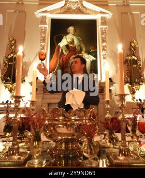 Evan Samson, der das Front-of-House-Team im Dumfries House leitet, überprüft die Gläser, während er dem Pink Dining Room, dem Lieblingszimmer des Königs im Dumfries House in Cumnock, Ayrshire, den letzten Schliff verleiht, wo Mitglieder der Öffentlichkeit die Möglichkeit erhalten, ein fest aus dem 18. Jahrhundert im Rahmen eines neuen maßgeschneiderten Dining Experience der King's Foundation Charity zu genießen. Bilddatum: Donnerstag, 10. Oktober 2024. Stockfoto