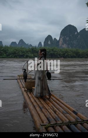 Hanfu-Mädchen mit Pipa-Instrument posiert für einen Fotografen an Bord eines kleinen Holzfloßes, China Stockfoto