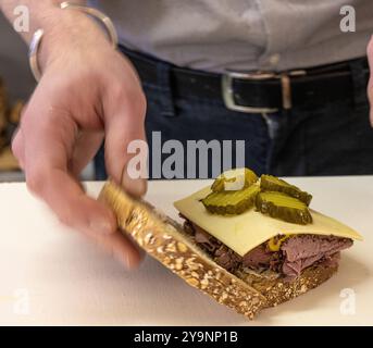 Nahaufnahme der Hand, die Pastrami-Sandwich auf Roggenbrot zubereitete Stockfoto