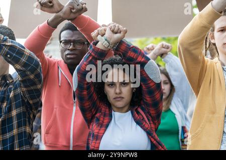 Eine Gruppe verschiedener junger Menschen, die bei einem Protest aus Solidarität Fäuste wecken. Das Bild zeigt die Stärkung der Jugend, Einheit in Vielfalt und Leidenschaft für Soci Stockfoto