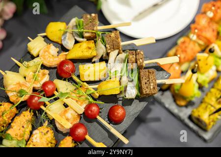 Vorspeisen auf Spießen, Desserts. Obst-Smoothie. Salate. Snacks. Snacks in Buffetform am Spieß im Catering Stockfoto