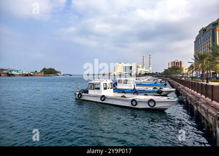 Damm im Hafen von Sharjah mit einer großen Moschee im Hintergrund, Vereinigte Arabische Emirate. Sharjah liegt an der Nordküste des Persischen Golfs Stockfoto