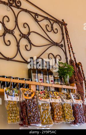 In Flaschen abgefülltes Olivenöl und Oliven mit Produkten auf Olivenbasis auf einem dekorativen Regal in einer griechischen Taverne auf der Insel Zante oder Zakynthos in Griechenland Stockfoto