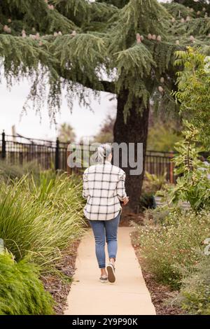 Frau, die einen Weg im Garten entlang geht Stockfoto