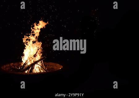 Knisterndes Lagerfeuer mit Funken, die in der dunklen Nacht fliegen. Stockfoto