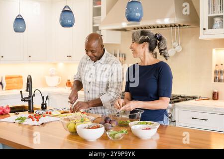 Ein Paar lächelt zusammen in der Küche beim Kochen Stockfoto