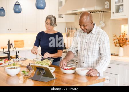 Ein Paar, das Essen in der Küche mit einer Tablette zubereitet Stockfoto