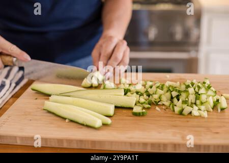 Frauenhände hacken eine Gurke Stockfoto