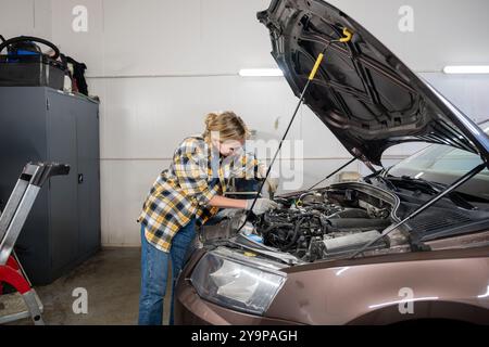 Weibliche Mechanikerin, die in der Garage an einem Auto arbeitet Stockfoto