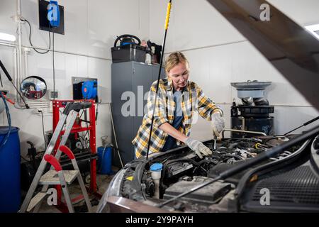 Weibliche Mechanikerin, die in der Garage an einem Auto arbeitet Stockfoto