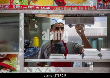 Mann, der in einem Halal-Wagen auf den Straßen in New York City in die Kamera schaut Stockfoto