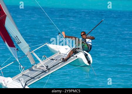 Randheli, Malediven - 24. Februar 2012: Ein maledivischer Segellehrer auf einem Katamaran von Hobie, während er den Kiel des Schiffes hochhält Stockfoto