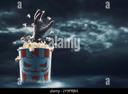 Gruselige Zombie-Hand aus einem Popcorn-Eimer: Horrorfilme und Halloween-Konzept Stockfoto