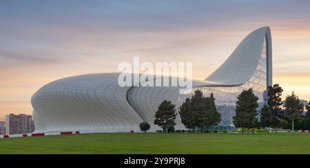 Das Heydar Aliyev Centre in Baku, Aserbaidschan, ist ein Beispiel für zeitgenössische Architektur mit seinem fließenden, wellenförmigen Design vor einem Sonnenuntergang Stockfoto