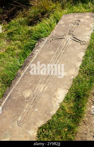 Das Schwert wurde auf einer Wegmarkierung am West Highland Way an der Stelle des Lochan of the Lost Sword in Tyndrum, Perthshire, Schottland, gehauen Stockfoto