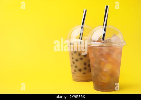 Leckerer Bubble Tea in Plastikbechern auf gelbem Hintergrund, Platz für Text Stockfoto