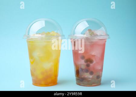 Leckerer Bubble Tee in Plastikbechern auf hellblauem Hintergrund Stockfoto