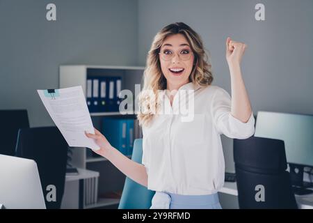 Foto eines hübschen jungen Mädchens, das Hold Papers gewinnt, Manager tragen formalbekleidete Kleidung, Coworking, erfolgreiches, nettes, leichtes Büro Stockfoto