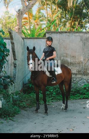 Teenager-Mädchen posiert zu Pferd in Reituniform und Helm. Stockfoto