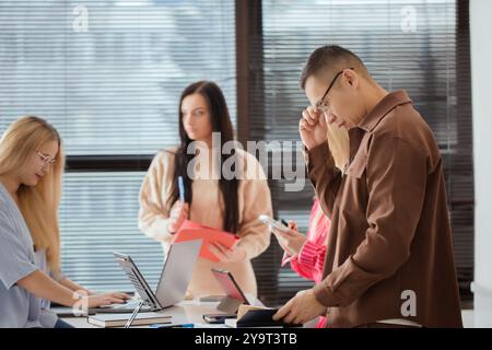 Eine Gruppe von Menschen sitzt mit Laptops und Papieren um einen Tisch. Sie diskutieren etwas Wichtiges Stockfoto