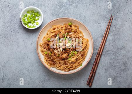 Dan Dan Dan Nudeln serviert mit Essstäbchen und grünen Zwiebeln, traditionelles chinesisches Sichuan-Gericht Stockfoto