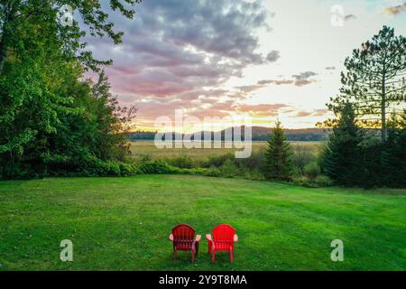 Tupper Lake NY Moody zwei rote Adirondack-Stühle mit Sonnenuntergang aus der Luft Stockfoto