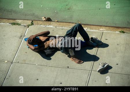 Obdachloser nutzt das warme Wetter, indem er sich am Montag, 30. September 2024, auf dem Bürgersteig in Chelsea in New York in der Sonne sonnt. (© Richard B. Levine) Stockfoto