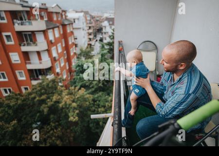 Vater und Baby genießen die Aussicht von einem Balkon an einem regnerischen Tag Stockfoto