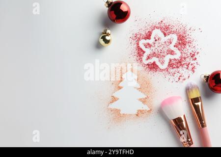 Weihnachtsdekorationen aus Puder und Rouge, Kugeln und Make-up-Pinsel auf weißem Hintergrund, flach gelegt. Leerzeichen für Text Stockfoto