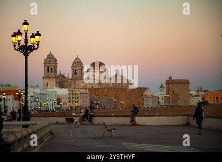 Cadiz, spanien - 5. Oktober 2024: Menschen auf dem Uferboulevard vor der Kathedrale von Cadiz bei Sonnenuntergang Stockfoto