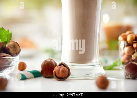 Detail des Haselnuss-Smoothies mit Glas und Nüssen auf einem Tisch. Vorderansicht. Stockfoto