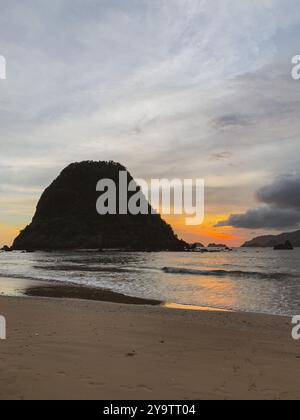 Atemberaubender Sonnenuntergang in Pulau Merah, Banyuwangi mit Silhouette der Insel und ruhigen Wellen des Ozeans Stockfoto