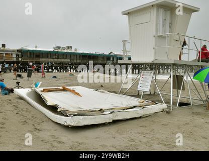 Cocoa Beach, Brevard County, Florida, USA. Oktober 2024. Der weltberühmte Cocoa Beach Pier erlitt große Schäden durch die Winde des Hurrikans Milton und ist heute für die Öffentlichkeit gesperrt. Hurrikanwinde drückten in einen Teil der Wand des Lagerraums und verursachten mehr Schaden. Surfer und Anblick spazieren an großen Dachabschnitten vorbei, die unten am Strand waren. Der Pier wurde durch vergangene Stürme beschädigt und kürzlich renoviert. Quelle: Julian Leek/Alamy Live News Stockfoto