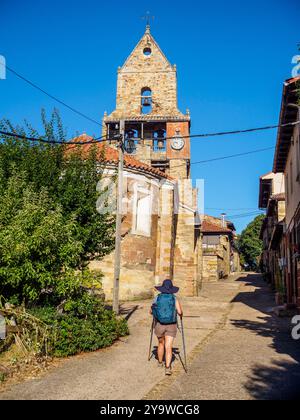 Ein Pilger mit Wanderstöcken geht zur Kirche Iglesia de la Asuncion in Rabanal del Camino, einem wichtigen Halt auf dem Jakobsweg. Spanien Stockfoto