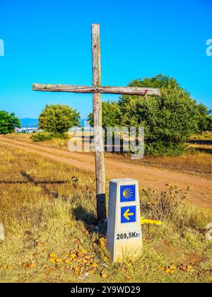 Ein hölzernes Kreuz steht neben einem Meilenstein des Jakobsweges, der 269,5 km verbleibt. Spanien. Stockfoto