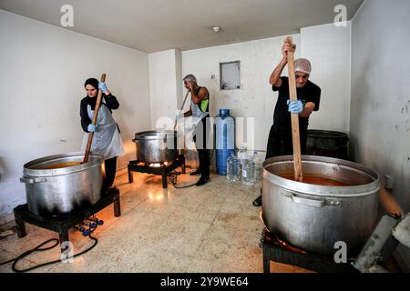 Beirut, Libanon. Oktober 2024. Freiwillige bereiten warme Mahlzeiten für vertriebene Libanesen zu, die aus ihren südlichen Dörfern und Häusern nach Beirut geflohen sind, in einer Wohltätigkeitsküche in Beirut. Hunderttausende Menschen sind aufgrund des eskalierenden Konflikts zwischen Israel und der pro-iranischen Hisbollah aus dem Südlibanon geflohen. Marwan Naamani/dpa/Alamy Live News Stockfoto