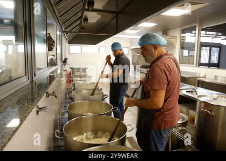 Libanon. Oktober 2024. Am 11. Oktober 2024 versammeln sich Menschen zur Zubereitung von Mahlzeiten für Einwanderer und Vertriebene in der Cuisine de Mariam, im Viertel Karantina in Beirut, Libanon. Cuisine de Mariam wurde am 8. August 2020, vier Tage nach der Doppelexplosion im Hafen von Beirut, von Pater Hani Tawk gegründet, der eine Garage in eine Küche umbaute, die für bedürftige Menschen aus allen Gemeinden offen war. CMA CGM finanziert Mariam's Kitchen seit 2022. Foto: Marc Fayad/ABACAPRESS. COM Credit: Abaca Press/Alamy Live News Stockfoto